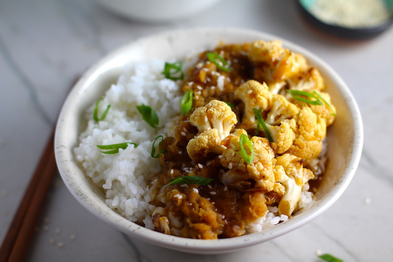 This Korean Rice Bowl on counter with Rice, Lentils and Cauliflower. This recipe is da bomb, exploding with flavor! The rice soaks up the sauce, which gives you a nutty, salty flavor from sesame oil and soy sauce, a warm and zesty kick from ginger and garlic, and sweetness from honey to balance it all out. Lentils and cauliflower give a meaty bite.