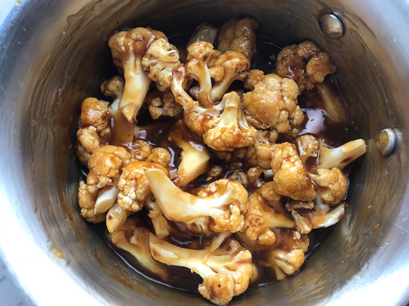 Roasted Cauliflower mixed in sauce in a pot for Korean Rice Bowl with Lentils and Cauliflower recipe, which is da bomb, exploding with flavor! The rice soaks up the sauce, which gives you a nutty, salty flavor from sesame oil and soy sauce, a warm and zesty kick from ginger and garlic, and sweetness from honey to balance it all out. Lentils and cauliflower give a meaty bite.