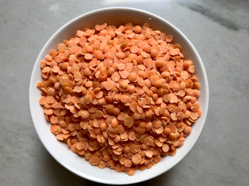 Uncooked Red Lentils in white bowl on counter for Korean Rice Bowl with Lentils and Cauliflower recipe, which is da bomb, exploding with flavor! The rice soaks up the sauce, which gives you a nutty, salty flavor from sesame oil and soy sauce, a warm and zesty kick from ginger and garlic, and sweetness from honey to balance it all out. Lentils and cauliflower give a meaty bite.