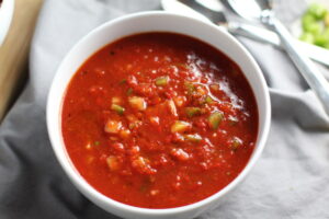 This Roasted Red Pepper Gazpacho recipe is Summer in a bowl - cool, tangy, crunchy, fresh, and creamy. The base is tomato, but this Gazpacho recipe puts Roast Red Pepper in the starring role, which brings another layer of creamy sweetness. Then you get the crunch from the green pepper, cucumber, garlic and scallions.