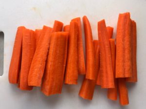 Raw cut carrot sticks on a white cutting board. Roasted Carrot fries with smoky cumin and scallions, then topped with Avocado Crema are such a delicious and quick side dish for dinner. Roasting brings out the natural sugar in the carrots, so they get a sweet caramelization with the salty and smoky flavors. The Avocado crema gives creamy and silky balance.