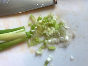 sliced scallions with knife on cutting board. Roasted Carrots with smoky cumin and scallions, then topped with Avocado Crema are such a delicious and quick side dish for dinner. Roasting brings out the natural sugar in the carrots, so they get a sweet caramelization with the salty and smoky flavors. The Avocado crema gives creamy and silky balance.