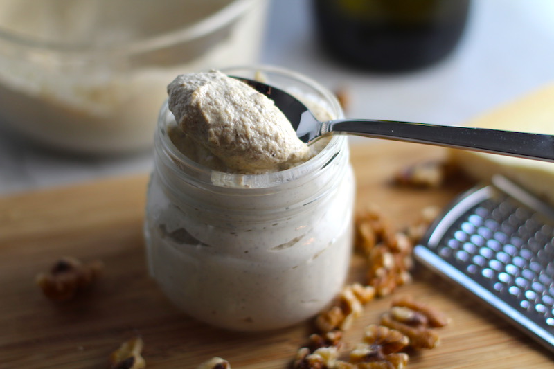 Walnut Cream Sauce in a jar on cutting board with walnuts next to it. Bowl in back. This recipe has ricotta cheese and parmesan with spinach and is thick, rich, nutty, and creamy. It's inspired by the traditional Italian Walnut Sauce from the North-Western Italy, Liguria Region, but my Walnut Sauce recipe adds even more decadence with creamy ricotta and more nutty parmesan cheese.
