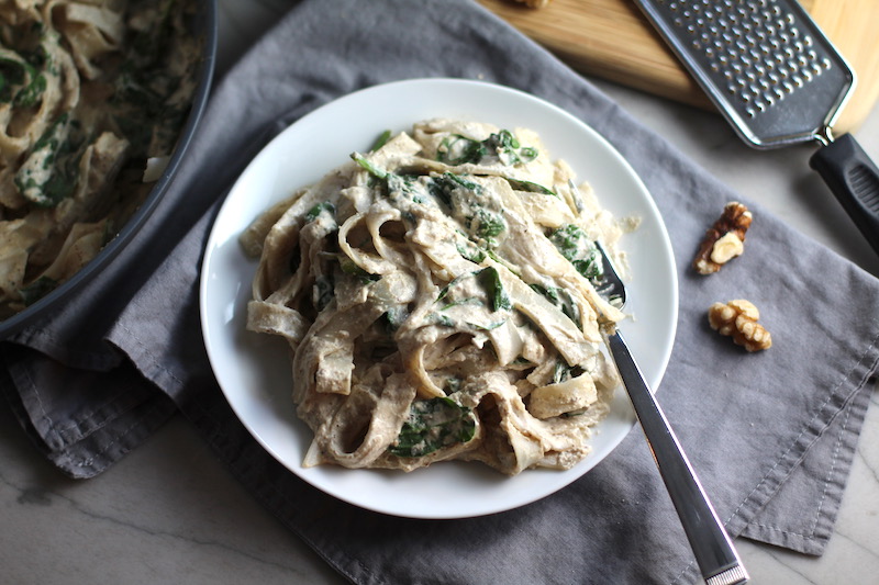 Walnut Sauce mixed with fettuccine and spinach on a plate with a fork. This Walnut Sauce recipe with Ricotta and Spinach is thick, rich, nutty, and creamy. It's inspired by the traditional Italian Walnut Sauce from the North-Western Italy, Liguria Region, but my Walnut Sauce recipe adds even more decadence with creamy ricotta and more nutty parmesan cheese.