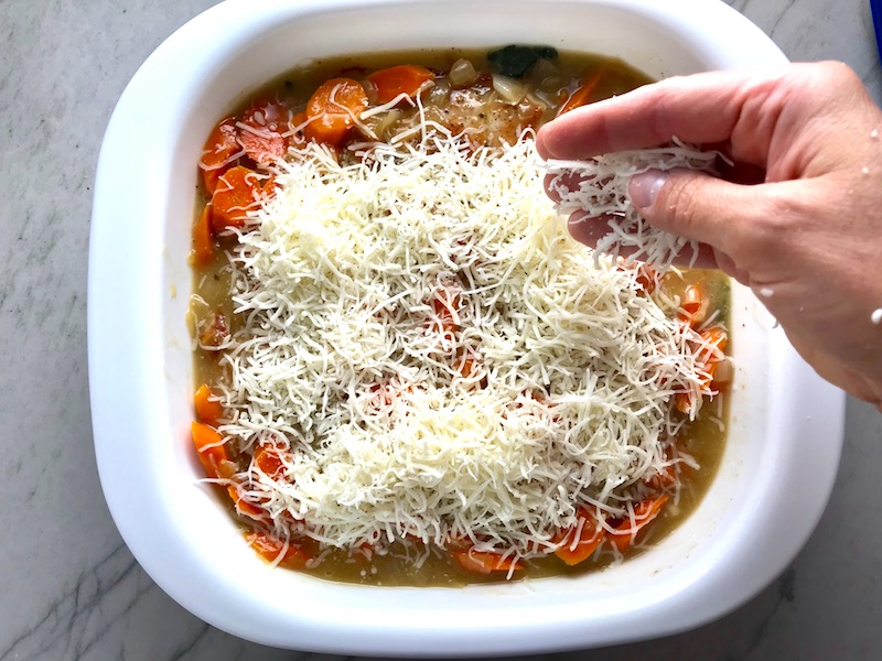 Hand sprinkling shredded mozzarella cheese over carrots, sauce, and pork in casserole dish. Smothered Pork Chop Casserole is a true midwestern comfort dish with layers of vegetables and meaty pork chops smothered in a creamy sauce and cheese. The pork chops in this delicious casserole are left whole so that you get an entire portion dripping in goodness in one scoop.