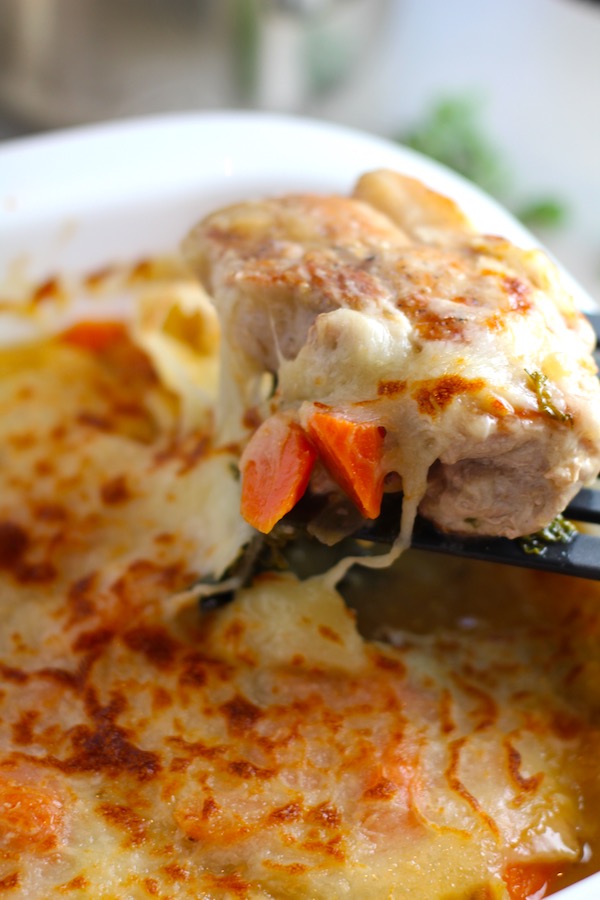 spatula lifting pork chop and carrots with cheese pulling. Smothered Pork Chop Casserole is a true midwestern comfort dish with layers of vegetables and meaty pork chops smothered in a creamy sauce and cheese. The pork chops in this delicious casserole are left whole so that you get an entire portion dripping in goodness in one scoop.