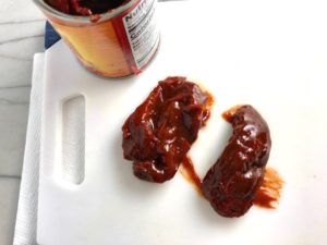 2 whole chipotle peppers in adobo sauce on cutting board next to can for Chipotle Chicken Enchilada Stew. It is one of my Prepped Freezer Meal recipes and it's creamy, cozy, hearty, cheesy, and slightly spicy. All ingredients freeze raw, thaw, then cook in the slow cooker or in the oven. It's a stew because it's thick and hearty with bites of chicken, carrots, onion, chipotle peppers, cumin, garlic and tortilla chips that melt down to thicken this delicious stew.