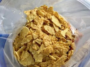 Crushed tortilla chips added to freezer bag for Chipotle Chicken Enchilada Stew. It is one of my Prepped Freezer Meal recipes and it's creamy, cozy, hearty, cheesy, and slightly spicy. All ingredients freeze raw, thaw, then cook in the slow cooker or in the oven. It's a stew because it's thick and hearty with bites of chicken, carrots, onion, chipotle peppers, cumin, garlic and tortilla chips that melt down to thicken this delicious stew.