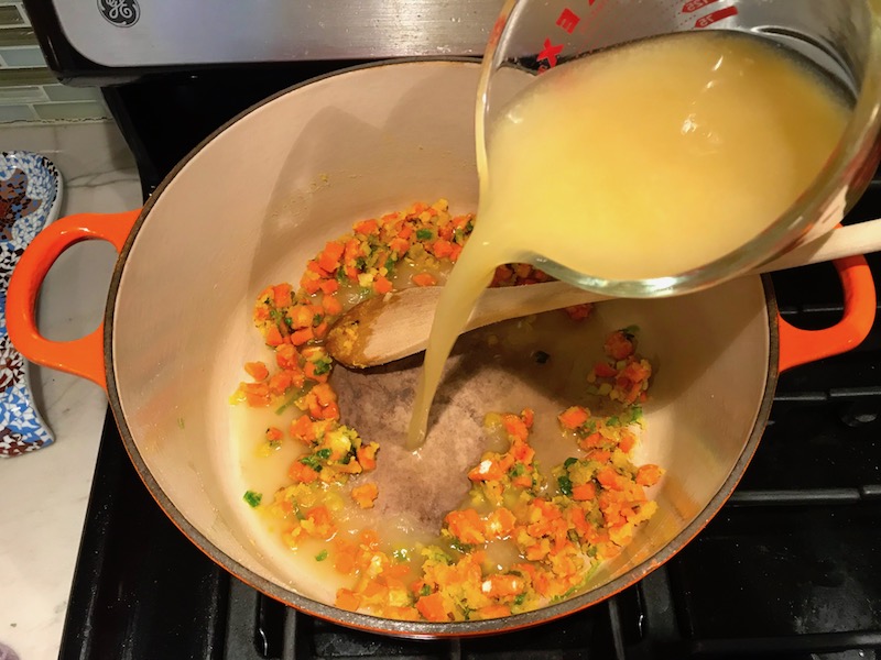Broth pouring over diced carrots and scallions mixed with flour in pot for Stove top Easy Tuna Casserole. This is a creamy and delicious comfort dish with tuna and noodles and a surprise pop of sweet from Pimiento. This easy recipe is completely from scratch (no canned soup here!) but I can promise you it's so easy and only takes 30 minutes because it's a Casserole that you can make entirely on the stove top!