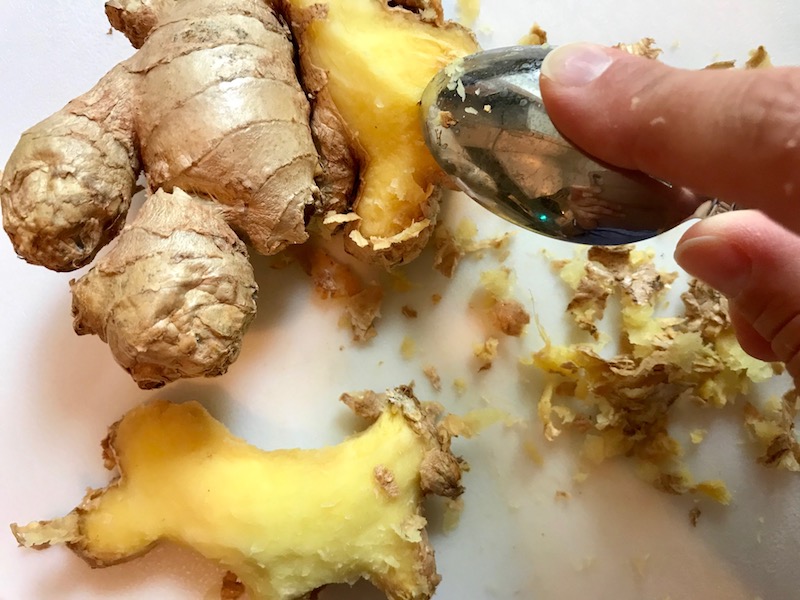 Whole ginger root with a spoon scraping off skin for Freezer Hoisin Chicken with Red Peppers, Carrots, Onions, Ginger, and Soy sauce is delicious and so easy to make. You get sweet and savory all in one dish and it's perfect for kids because it's sweet, not spicy at all. Just freeze ahead, thaw, then cook on a sheet pan!