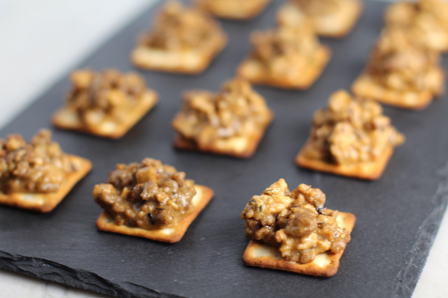 Cooked Hanky Panky on Black Slate Platter. These Hanky Panky Canapes are the BEST Party Appetizers around! They cheesy, meaty, and absolutely delicious. Ground Beef is mixed with Homemade Chicken Sausage and then combined with lots of cheese until its a creamy addictive pot of goodness. Then it is scooped on top of bread, toasts, or crackers