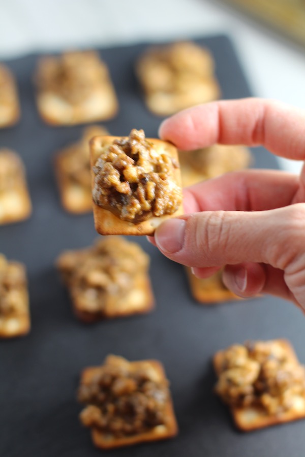 Hand holding a Hanky Panky. These Hanky Panky Canapes are the BEST Party Appetizers around! They cheesy, meaty, and absolutely delicious. Ground Beef is mixed with Homemade Chicken Sausage and then combined with lots of cheese until its a creamy addictive pot of goodness. Then it is scooped on top of bread, toasts, or crackers