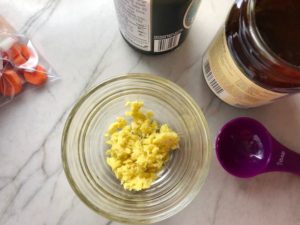 Minced ginger in a small bowl on counter with other ingredients for this Freezer Hoisin Chicken with Red Peppers, Carrots, Onions, Ginger, and Soy sauce is delicious and so easy to make. You get sweet and savory all in one dish and it's perfect for kids because it's sweet, not spicy at all. Just freeze ahead, thaw, then cook on a sheet pan!