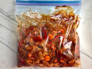 All raw ingredients in freezer bag for Freezer Hoisin Chicken with Red Peppers, Carrots, Onions, Ginger, and Soy sauce is delicious and so easy to make. You get sweet and savory all in one dish and it's perfect for kids because it's sweet, not spicy at all. Just freeze ahead, thaw, then cook on a sheet pan!