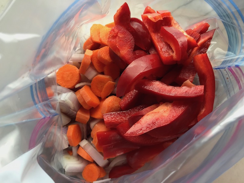 Sliced Carrots and sliced red pepper added to bag for his Freezer Hoisin Chicken with Red Peppers, Carrots, Onions, Ginger, and Soy sauce is delicious and so easy to make. You get sweet and savory all in one dish and it's perfect for kids because it's sweet, not spicy at all. Just freeze ahead, thaw, then cook on a sheet pan!