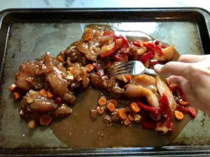Fork spreading out the Hoisin chicken and peppers, carrots, and onions, on sheet pan. This Freezer Hoisin Chicken with Red Peppers, Carrots, Onions, Ginger, and Soy sauce is delicious and so easy to make. You get sweet and savory all in one dish and it's perfect for kids because it's sweet, not spicy at all. Just freeze ahead, thaw, then cook on a sheet pan!