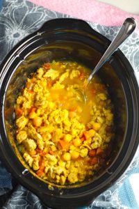 Moroccan Chicken Chili with Chickpeas in a Slow Cooker Pot with spoon n blue towel. Its loaded with comforting and healthy ingredients and spices. You get warmth from Ginger, Turmeric, Garlic, and Coriander. Then tons of hearty flavor from browned ground chicken and Shallots. And creaminess from the Carrots and Chickpeas. You can make it ahead and freeze it until you are ready to cook it!