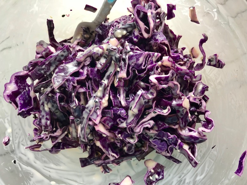 Sesame Asian Slaw in bowl for Asian Lettuce Wraps. They are a fantastic way to use leftover Turkey or Chicken transforming it with new delicious flavors and textures. The turkey is stir fried with carrots, red pepper, and brussel sprouts in a flavorful ginger, garlic, & sesame sauce. It's layered in lettuce wraps with rice and a cool, crunchy purple cabbage sesame slaw. Serve with a Garlic Honey Soy Sauce....YUM!!!