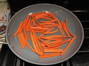 Carrot slices in pan for Asian Lettuce Wraps. They are a fantastic way to use leftover Turkey or Chicken transforming it with new delicious flavors and textures. The turkey is stir fried with carrots, red pepper, and brussel sprouts in a flavorful ginger, garlic, & sesame sauce. It's layered in lettuce wraps with rice and a cool, crunchy purple cabbage sesame slaw. Serve with a Garlic Honey Soy Sauce....YUM!!!