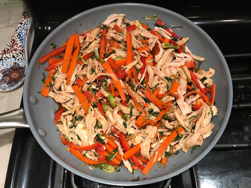 Shredded Turkey and stir fry veggies in pan for Asian Lettuce Wraps. They are a fantastic way to use leftover Turkey or Chicken transforming it with new delicious flavors and textures. The turkey is stir fried with carrots, red pepper, and brussel sprouts in a flavorful ginger, garlic, & sesame sauce. It's layered in lettuce wraps with rice and a cool, crunchy purple cabbage sesame slaw. Serve with a Garlic Honey Soy Sauce....YUM!!!
