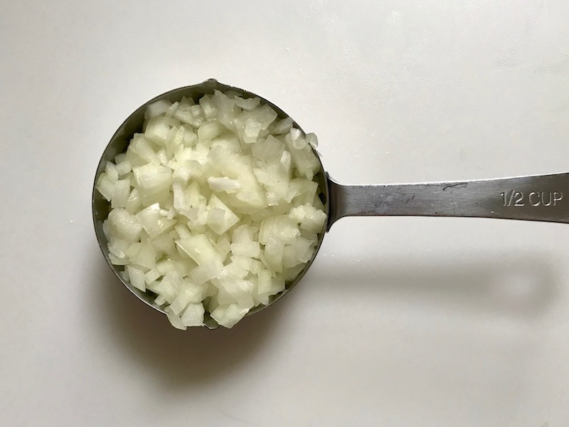 Cut raw onions in measuring cup for Easy Bacon Brussel Sprouts and Chicken recipe. It's a perfect quick Fall Recipe! It has a creamy sauce filled with salty bacon, earthy and almost nutty seared brussel sprouts, and hearty healthy chicken. Serve over rice (or Quinoa or pasta!).