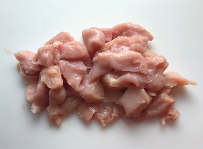 Cut raw chicken for Easy Bacon Brussel Sprouts and Chicken recipe. It's a perfect quick Fall Recipe! It has a creamy sauce filled with salty bacon, earthy and almost nutty seared brussel sprouts, and hearty healthy chicken. Serve over rice (or Quinoa or pasta!).