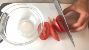 Slicing Plum Tomato for Bruschetta topping. It combines fresh tomatoes, artichoke hearts, garlic, basil, olive oil, and GOAT CHEESE! Top on toasty garlic crostini and you get fresh bright flavors with both crunch and creamy in every bite.