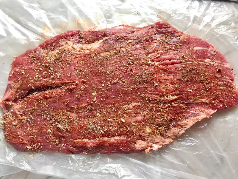 Spices rubbed on raw Flank Steak Rub. This Flank Steak Recipe with Potatoes & Broccoli is an easy and delicious Sheet Pan Dinner. It has a flavorful rub and a tangy, light Garlic Chive Crema!