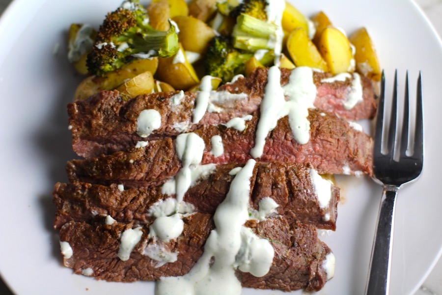 Flank Steak sliced with Potatoes & Broccoli on plate with crema drizzled on top. This is an easy and delicious Sheet Pan Dinner. The homemade steak rub adds such wonderful flavor. To top this sheet pan dinner, you get this tangy, light Garlic Chive Crema! Best of all, you only need 1 pan so it's a super easy clean up. Easy and Delicious!