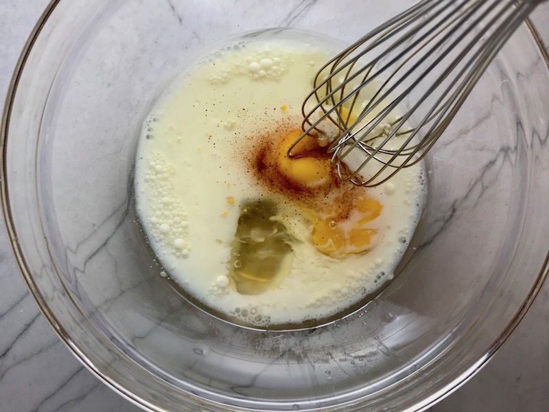 Wet ingredients in bowl for Cheddar Honey Cornbread piece in hand with more in background. It brings the salty and sweet combo to life spectacularly - particularly when the aromas from the honey, corn, and cheddar fill your house. This Gluten Free version is moist, slight salty from the cheese, slightly sweet from the honey and cornmeal. It's the perfect holiday meal side, whether it's breakfast, brunch, or dinner.