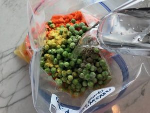 Pitcher pouring water to added to Freezer Bag for a 5-Ingredient Homemade Chicken Soup. It's thick, creamy, and hearty. It's filled with flavorful broth, meaty shredded chicken, and sweet bursts of bright veggies. You can prepare all of the ingredients ahead and freeze them until you are ready to cook. Then, thaw, pour into the Slow Cooker, set and forget.