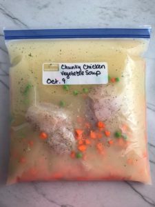 5-Ingredient Homemade Chicken Soup ingredients in a labeled Freezer Bag. This recipe is thick, creamy, and hearty. It's filled with flavorful broth, meaty shredded chicken, and sweet bursts of bright veggies. You can prepare all of the ingredients ahead and freeze them until you are ready to cook. Then, thaw, pour into the Slow Cooker, set and forget.
