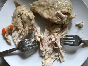 Two forks shredding cooked chicken for 5-Ingredient Homemade Chicken Soup. This soup is thick, creamy, and hearty. It's filled with flavorful broth, meaty shredded chicken, and sweet bursts of bright veggies. You can prepare all of the ingredients ahead and freeze them until you are ready to cook. Then, thaw, pour into the Slow Cooker, set and forget.