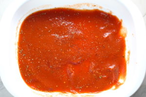 Tomato sauce at bottom of casserole dish for Turkey Ricotta Stuffed Shells in Tomato Sauce. These are the perfect way to repurpose and transform leftover Turkey or Chicken. The Shredded Turkey, Italian seasonings, mozzarella, and ricotta are stuffed in shells and topped with a simple tomato sauce and more melty mozzarella and nutty parmesan, it's a perfect dish that the family will love!