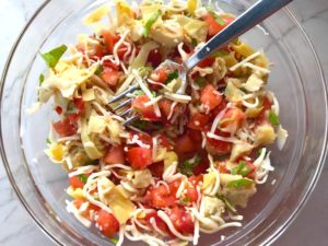 Tomato, artichoke, mozzarella in bowl for the Tomato Tart Recipe. It gives you crunch from the Quinoa crust, a burst of fresh from the tomatoes, tons of flavor from the basil and garlic, tang and meatiness from the artichoke and so much creaminess from the mozzarella and goat cheese! It's addictive and delicious!
