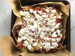 Quinoa crust Tomato, Artichoke, and goat cheese tart in pan with parchment paper for the Tomato Tart Recipe. It gives you crunch from the Quinoa crust, a burst of fresh from the tomatoes, tons of flavor from the basil and garlic, tang and meatiness from the artichoke and so much creaminess from the mozzarella and goat cheese! It's addictive and delicious!