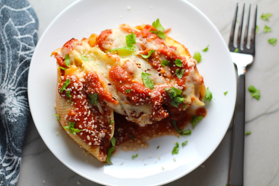 Turkey Ricotta Stuffed Shells in Tomato Sauce on plate with casserole dish in background. These are the perfect way to repurpose and transform leftover Turkey or Chicken. The Shredded Turkey, Italian seasonings, mozzarella, and ricotta are stuffed in shells and topped with a simple tomato sauce and more melty mozzarella and nutty parmesan, it's a perfect dish that the family will love!