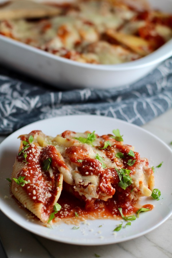 leftover turkey pasta bake Stuffed Shells in Tomato Sauce on plate with casserole dish in background. These are the perfect way to repurpose and transform leftover Turkey or Chicken. The Shredded Turkey, Italian seasonings, mozzarella, and ricotta are stuffed in shells and topped with a simple tomato sauce and more melty mozzarella and nutty parmesan, it's a perfect dish that the family will love!