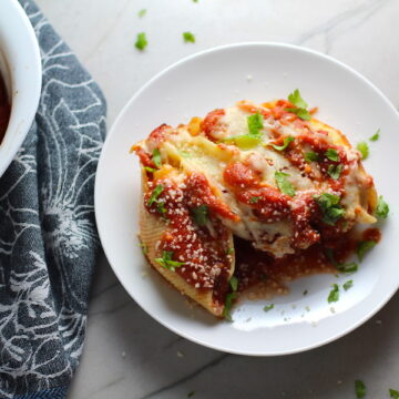 leftover turkey pasta bake Stuffed Shells in Tomato Sauce on plate with casserole dish in background. These are the perfect way to repurpose and transform leftover Turkey or Chicken. The Shredded Turkey, Italian seasonings, mozzarella, and ricotta are stuffed in shells and topped with a simple tomato sauce and more melty mozzarella and nutty parmesan, it's a perfect dish that the family will love!