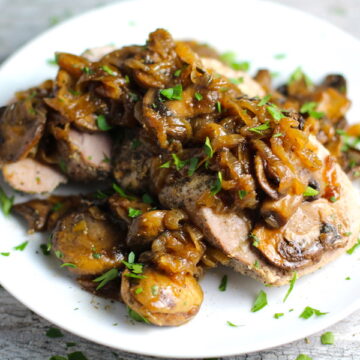 Caramelized Onions & Mushrooms on Sliced Pork Tenderloin on plate. This recipe is such a flavorful main dish! The pork tenderloin is moist and juicy and topped with Onions & Mushrooms that are sauteed low and slow with a touch of balsamic to bring out all of the natural sugars and caramelize them to perfection.