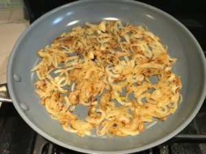 Sliced onions cooking in skillet for the Caramelized Onions & Mushrooms on Pork Tenderloin recipe. This is such a flavorful main dish! The pork tenderloin is moist and juicy and topped with Onions & Mushrooms that are sauteed low and slow with a touch of balsamic to bring out all of the natural sugars and caramelize them to perfection.