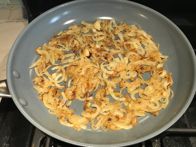 Sliced onions cooking in skillet for the Caramelized Onions & Mushrooms on Pork Tenderloin recipe. This is such a flavorful main dish! The pork tenderloin is moist and juicy and topped with Onions & Mushrooms that are sauteed low and slow with a touch of balsamic to bring out all of the natural sugars and caramelize them to perfection.