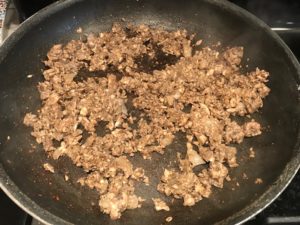 Mushroom stuffing cooking in pan. This Stuffed Flank Steak recipe is oozing with flavor! First, you get mushrooms, onions, and garlic sauteed together. Then they are mixed with fresh parsley and basil, then parmesan, and goat cheese! Roll it all up in Flank Steak and roast for an amazing dinner.