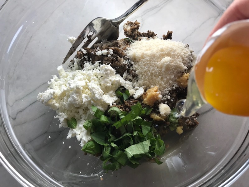 Mushrooms, parmesan, goat cheese, basil, parsley, garlic, and egg whites added to bowl for stuffing. This Stuffed Flank Steak recipe is oozing with flavor! First, you get mushrooms, onions, and garlic sauteed together. Then they are mixed with fresh parsley and basil, then parmesan, and goat cheese! Roll it all up in Flank Steak and roast for an amazing dinner.