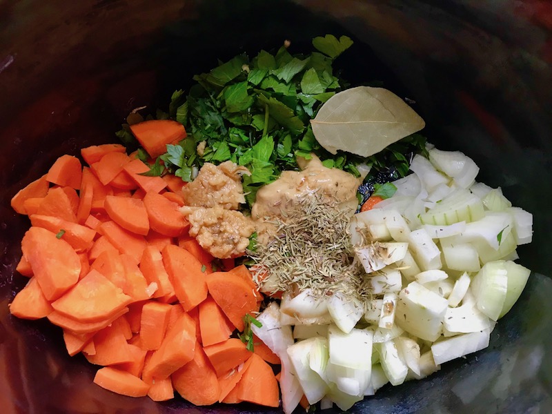Carrots, onion, and other ingredients in crockpot for the Slow Cooker Beef Stew over Noodles recipe. It's comfort food full of flavor and texture with carrots, onion, garlic, thyme, beef, and more. Now, try pouring that salty, chunky, saucy goodness over noodles...yup, even more amazing! #beefstew #crockpot #slowcooker #easydinners #dinnerrecipes