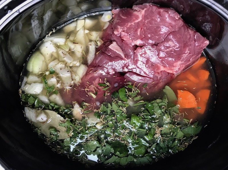 Beef, carrots, onion, broth, and other ingredients in crockpot for the Slow Cooker Beef Stew over Noodles recipe. It's comfort food full of flavor and texture with carrots, onion, garlic, thyme, beef, and more. Now, try pouring that salty, chunky, saucy goodness over noodles...yup, even more amazing! #beefstew #crockpot #slowcooker #easydinners #dinnerrecipes
