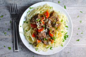 Slow Cooker Beef Stew over Noodles on a plate. This is downhome comfort food that's full of flavor and texture with carrots, onion, garlic, thyme, beef, and more. Now, try pouring that salty, chunky, saucy goodness over noodles...yup, even more amazing!#beefstew #crockpot #slowcooker #easydinners #dinnerrecipes