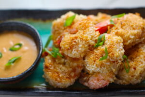 Baked Coconut Shrimp on plate with Sriracha Sauce. Crunchy and utterly irresistible, this 30-Minute Baked Coconut Shrimp recipe is one that you have got to try! They are baked, not fried, so they are EASY to cook and HEALTHIER for you too!