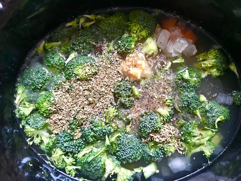 Oregano, salt, and pepper added to broccoli florets, diced carrot, and onion with broth in crockpot for a Light Slow Cooker Creamy Broccoli Soup. This is easy, comforting, and delicious! With Carrots, Broccoli, Onion, Garlic, and Oregano, this is one flavorful soup. And, there is no heavy cream, just milk and a little half and half mixed with cornstarch, so it's healthy and gluten free!