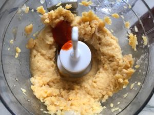 Blended Chickpeas and Sriracha in food processor for Magical Sriracha Hummus. This recipe is seriously the easiest hummus you will ever make and it's perfect for snacking or adding to a meal. The chickpeas have so much flavor and the Sriracha gives it a kick that is totally addictive!